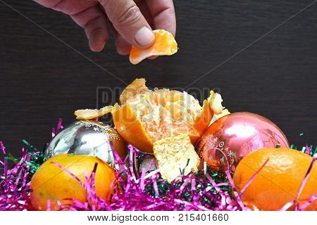 Christmas tree toys on red napkin. Mandarins and candles on the table. A fur-tree branch and fruit on a New Year's table.