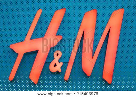 Vilnius, Lithuania - September 21, 2017: Close The Illuminated Red Logotype H M Of Hennes Mauritz Brand At Blue Wall Of Store In Shopping Center.
