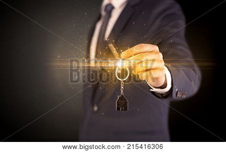 Businessman hand  over shiny keys in dark suit with dark background