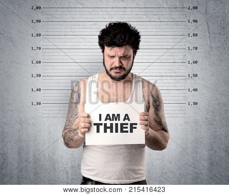 Caugth offender in front of a wall with table in his hand.