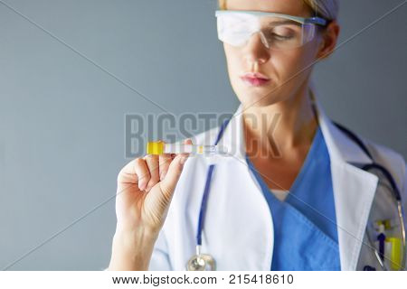 Female medical or research scientist or doctor using looking at a test tube of clear solution in a lab or laboratory