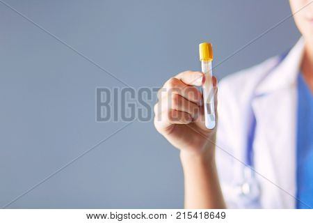Female medical or research scientist or doctor using looking at a test tube of clear solution in a lab or laboratory