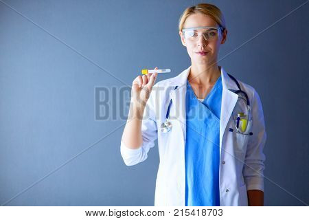 Female medical or research scientist or doctor using looking at a test tube of clear solution in a lab or laboratory