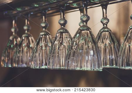 Glasses hanging on bar rack close up. Clean utensil for wine in restaurant, barroom background