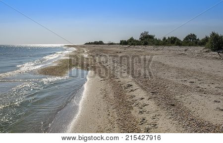 On a hot cloudless day the waves rolled ashore sandy beach. Island Dzharylgach. Black Sea.