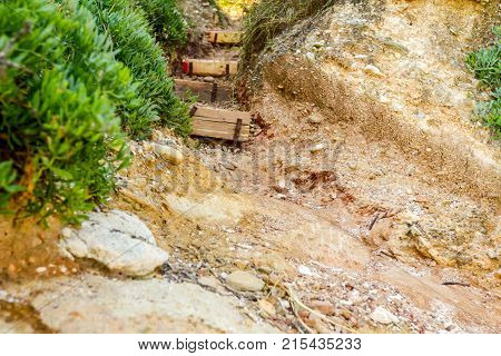 Narrow passage through corridor in rock with carved stairs.