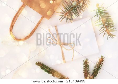 Festive sparkling winter season holidays background. Top view preparation gifts, pine tree twigs, paper bag.