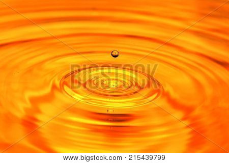 a drop of water falls in a golden water. macro .