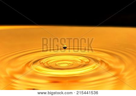a drop of water falls in a golden water. macro .