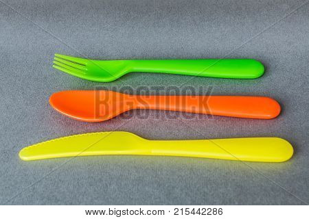 a set of colorful plastic Cultery: spoon fork knife on gray background.