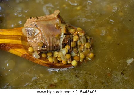 lentil soup with meat to cook in the pan with a wooden spoon