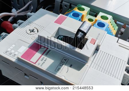 Modern power circuit breaker with adjustable and terminals in electrical Cabinet. Electric wires connected to the circuit breaker and the terminals and laid in a cable channel. Distribution of electricity with the help of qualitative components.