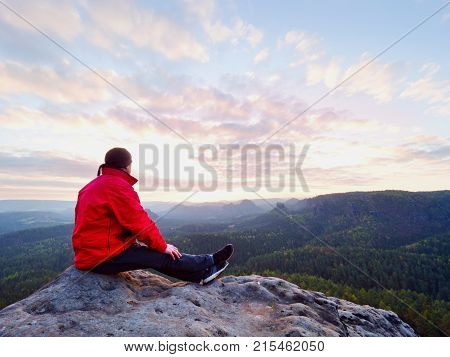 Sitting Hiker On Rock.  Man In Red Black  Warm Clothes Is Sitting On Cliff And Enjoying Far View.