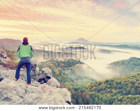 Man Stay On Rocky Peak Within Daybreak And Watch Over Misty Landscape.