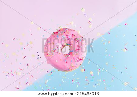 one falling sweet doughnut with sprinkles on blue and pink abstract background with copy space