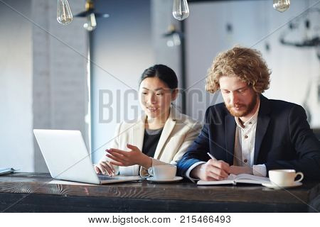 Young female making online presentation to co-worker at working meeting