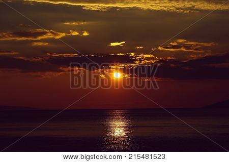 Spectacular dramatic dark sky at sunset with clouds over sea or ocean water horizon on evening seascape on natural background