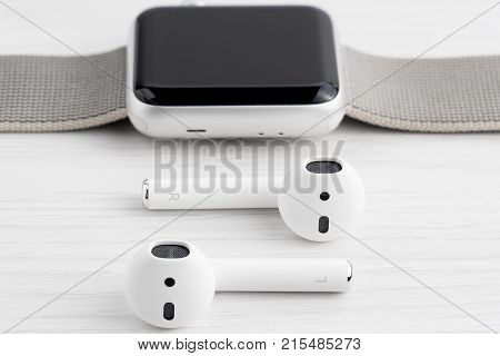 UFA RUSSIA - OCTOBER 20 2017: AirPods wireless headphones developed by Apple Inc. AirPods are on the table and apple watch.