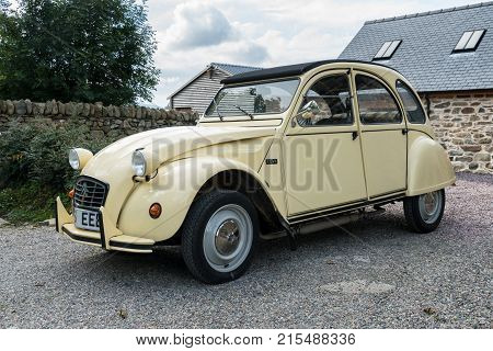 OSWESTRY, UK - SEPTEMBER 24, 2016: Restored cream colored Citroen 2CV6 french car in driveway of old house