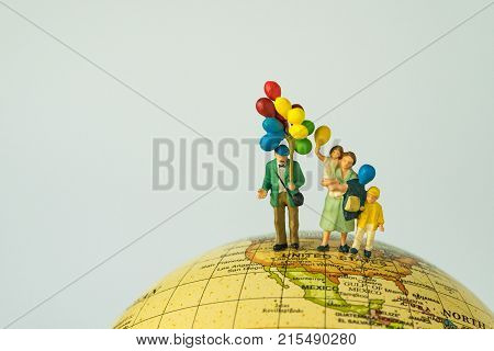 miniature people figure happy family holding balloons standing on united states of america map on globe as world climate change or happy american family concept.
