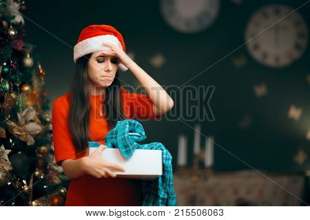 Upset Girl Opening a Bad Christmas Gift Finding Pajamas Inside