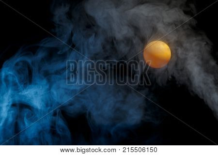 Orange tennis ball penetrating the space and the darkness.