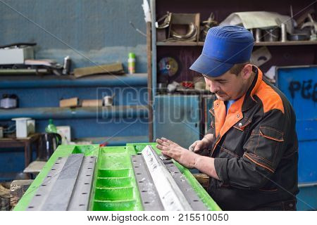 LIPETSK, RUSSIA - JUNE 15, 2017: Lipetsk Machine Tool Plant. Work on the preparation of the bed of a metal-cutting machine for assembly. The locksmith performs a manual scraping operation.
