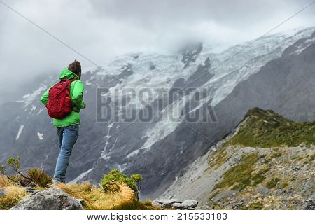New Zealand hiker man hiking, enjoying view of snow capped mountain landscape in Hooker Valley track. Alps alpine background Active hiker standing . Mountaineering sport lifestyle.