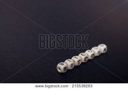 Cubes with letters on a black background. The word Bitcoin from cubes.