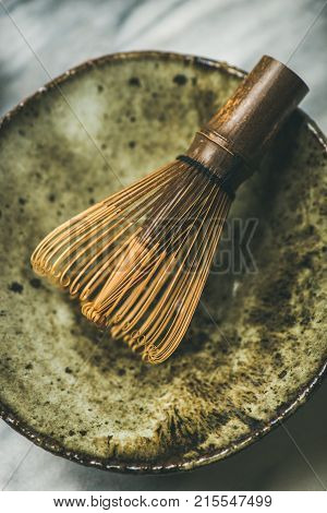 Flat-lay of Japanese tools for brewing matcha tea. Matcha powder in tin can, Chasen bamboo whisk, Chawan bowl over grey background, top view