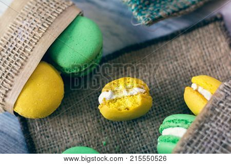 yellow and green macaroons in boxes packed with burlap. One of this is a bitten off