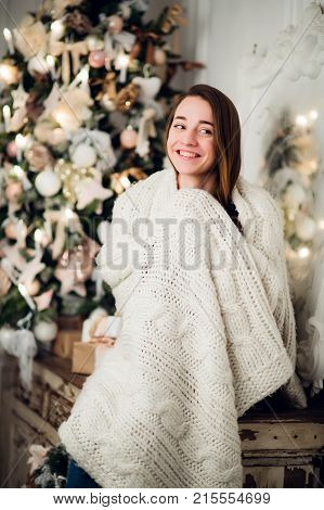Woman with a Christmas Gift sitting on acncient commode decorated for xmas. Fir tree at background.