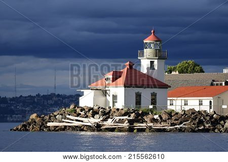 High contrast image of Seattle's Alki Point Lighthouse taken from the water on a cloudy sunlit day