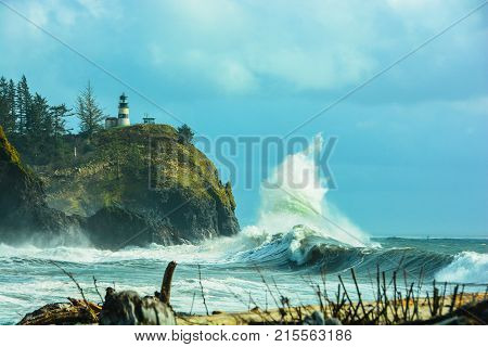 Waves breaking on Waimea Beach at Cap Disappointment with lighthouse in the background.