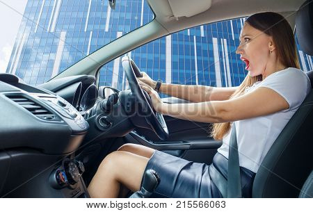 Young frightened driver woman squealing brakes. Shocked girl tooting horn in traffic jam