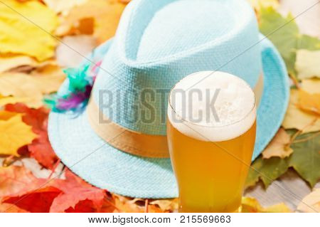 Beer glass pint octoberfest picnic on background with hat and autumn yellow leaves