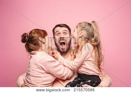Happy young family with one little daughter posing together on pink studio background