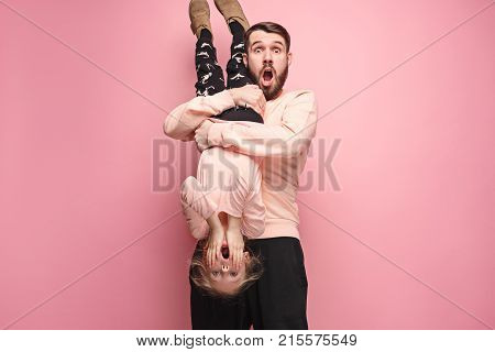 The surprised and cheerful father playing with daughter at pink studio