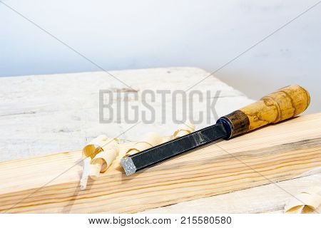A carpenter's tool. Chisel on a wooden bar. Next to the chisel shaving