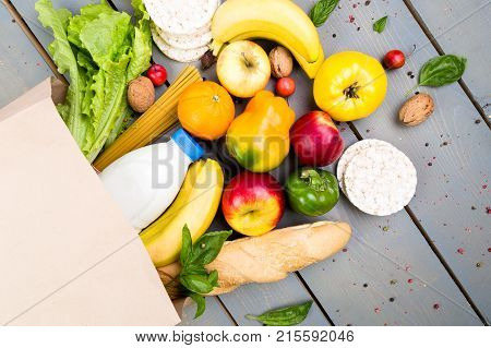 Grocery Shopping Concept. Different Food In Paper Bag On Wooden Background.  Flat Lay.