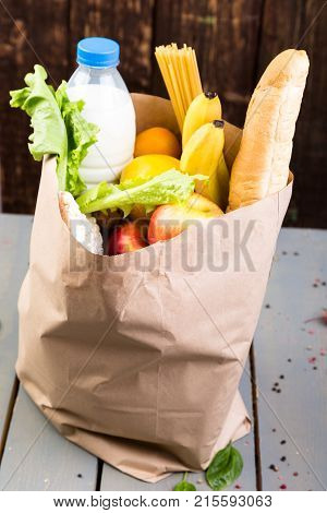 Grocery Shopping Concept. Different Food In Paper Bag On Wooden Background.