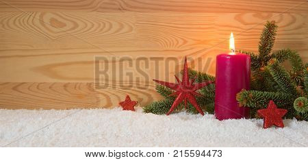 Avent candle and christmas decoration isolated on wood background. Christmas background with snow, candle and red stars.