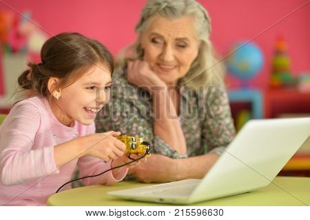 Grandmother and granddaughter playing computer games on laptop