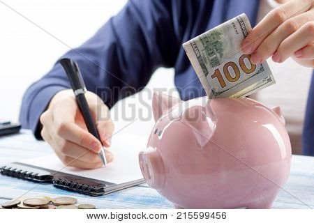 Hand putting coin into piggy bank closeup. selective focus