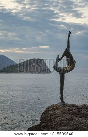 BUDVA MONTENEGRO - October 01 2017: Beautiful and elegant sculpture of a gymnast located on a rocky rock near the beach Morgen and the old town of Budva in Montenegro. It's often mistaken to be a ballet dancer.