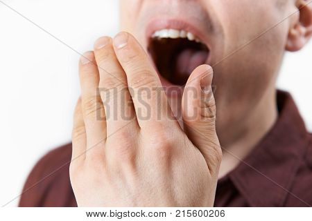 Studio Close Up Of Man Covering Mouth Whilst  Yawning