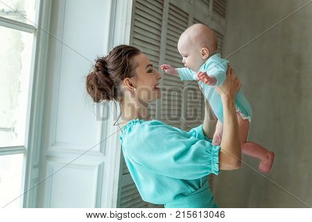 Mother holding her child. Young mother playing whith her daughter. Woman and new born girl relax at home. Mother breast feeding baby. Happy family at home. Young mother playing whith her newborn daughter