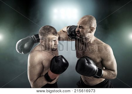 Two professional boxers, athletes in dynamic boxing action on the ring under lights of sport arena.