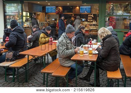 MUNICH, GERMANY - NOVEMBER 16, 2017: People eating street-food and drinking cold beer at outdoor cafe on November 16, 2017. Bavaria is famous for its breweries and the Weissbier - wheat beer