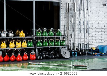 The sports hall with weights dumbbells bars on the background of a dark window and a gray brick wall